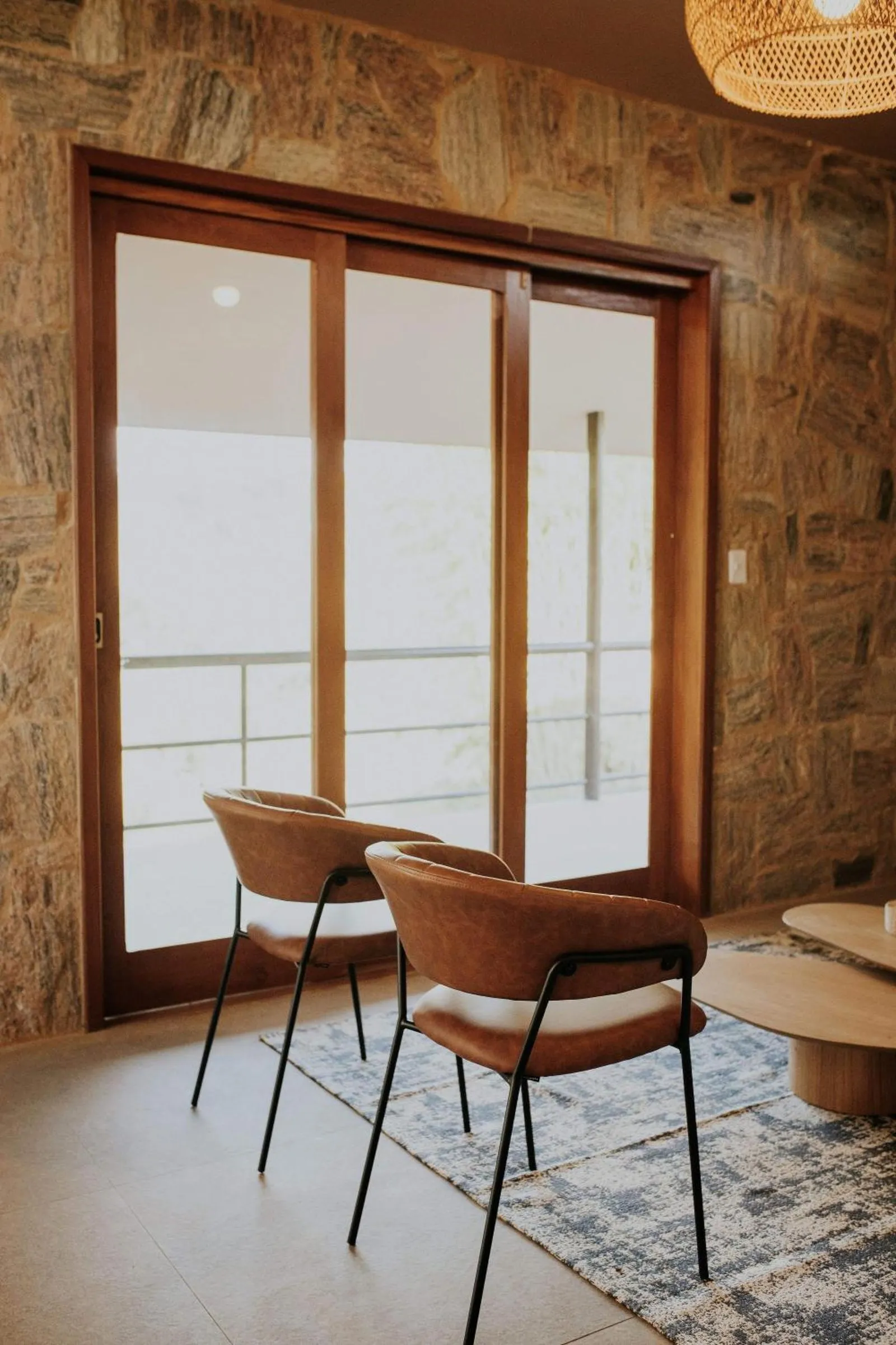 Poltronas junto à porta de vidro da cabana, com vista para fora